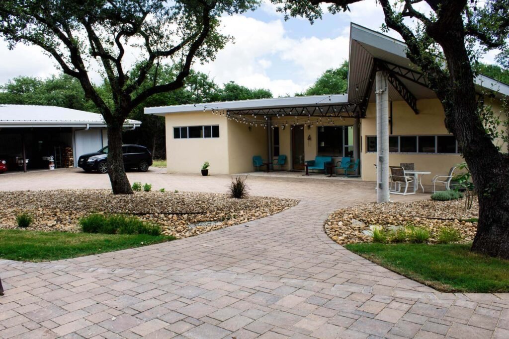 Modern driveway with a mix of concrete and natural stone, accented by greenery and stylish pathway lighting.